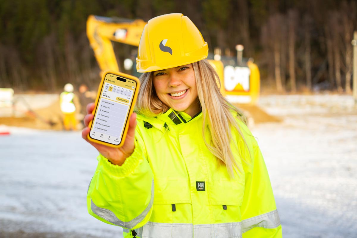 Jente med app foran gravemaskin